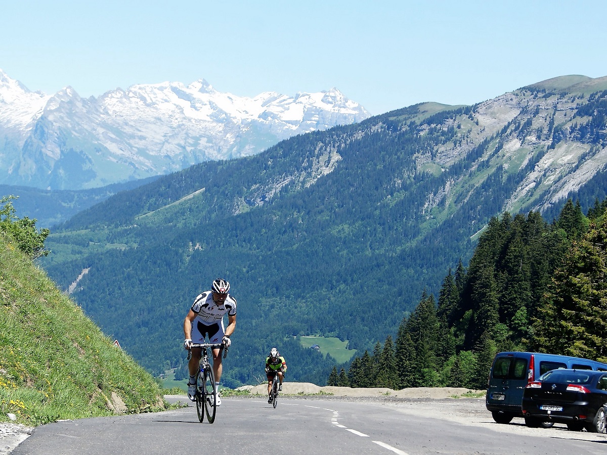 Cyclists climbing to the top of a mountain in the French Alps with snow in background