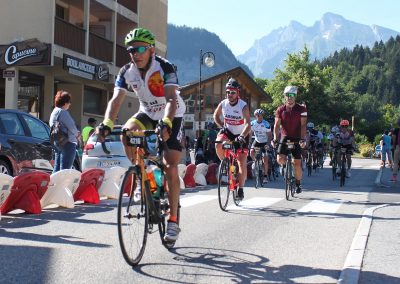 Cyclists riding through a village with mountains